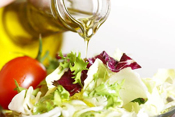 ภาพระยะใกล้ของน้ํามันมะกอกบริสุทธิ์ที่ถูกเทลงบนสลัดในสวน - salad oil ภาพสต็อก ภาพถ่ายและรูปภาพปลอดค่าลิขสิทธิ์