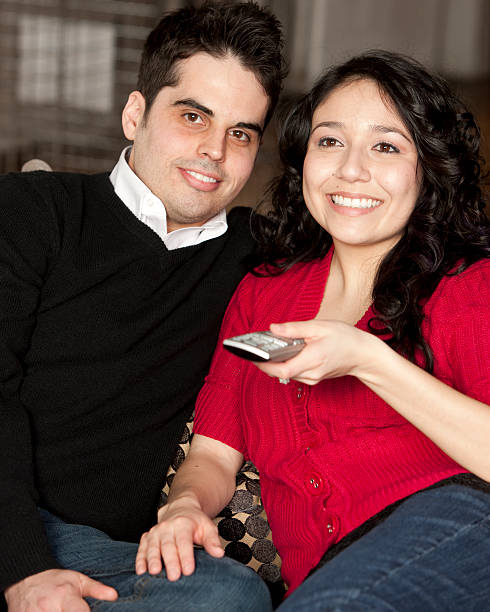 istock Couple Sits Together With Remote Control Watching Television 471227113