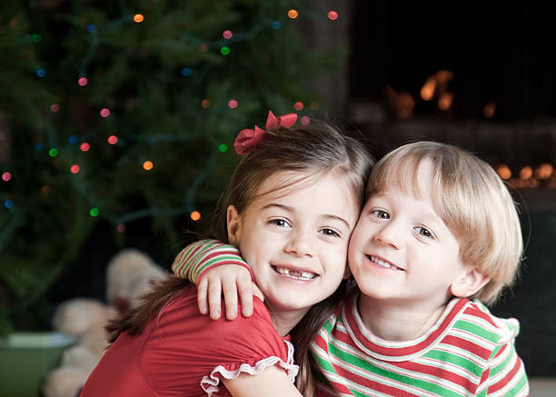 兄と妹のクリスマスの愛を - embracing smiling gap children only ストックフォトと画像
