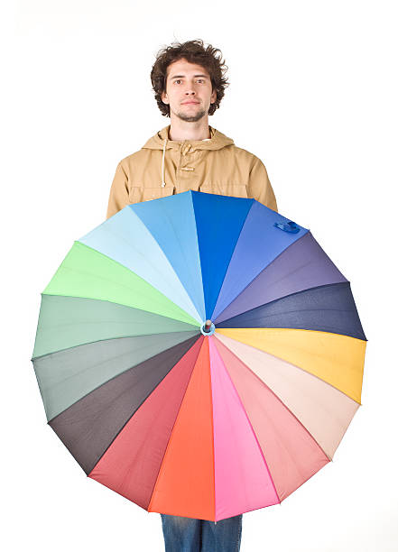 istock Handsome man in light brown vintage raincoat holding colorful umbrella. 471230672