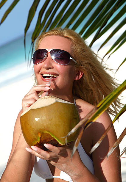 Beautiful blondy holding coconut in tropical beach stock photo