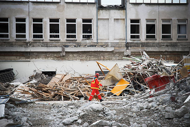 Rescue man walking on demolished building debris rescue man with dog searching for humans in a destroyed building search and rescue dog photos stock pictures, royalty-free photos & images