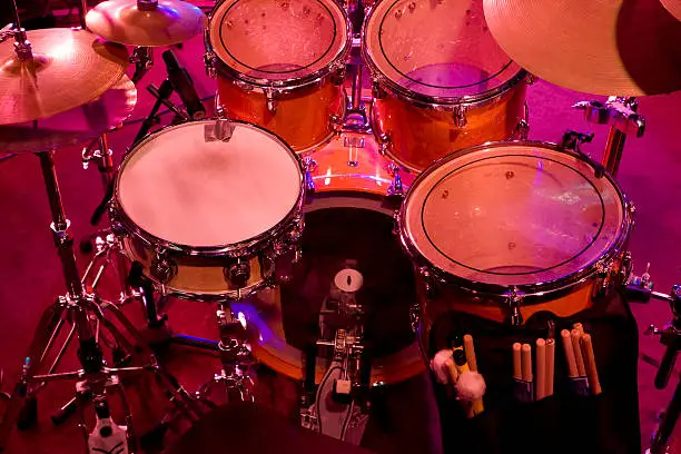 Drum kit reflecting the reds, blues and purples of the stage lighting.