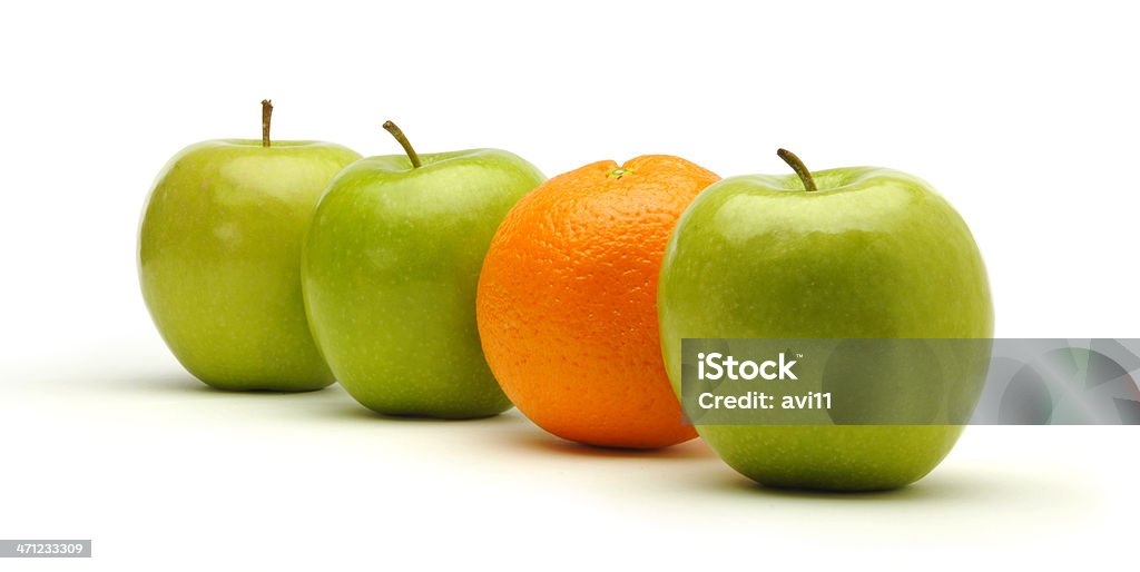 Trzy świeże zielone jabłka i jeden pomarańczowy. - Zbiór zdjęć royalty-free (Pomarańcza)