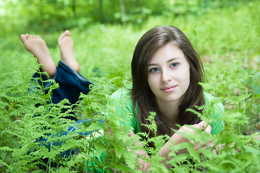 Beautiful young woman lying down In the ferns. 