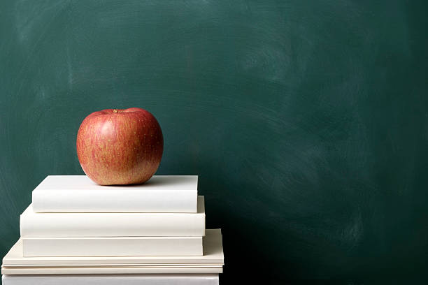istock Red apple on stacked blank books against blackboard 471235119