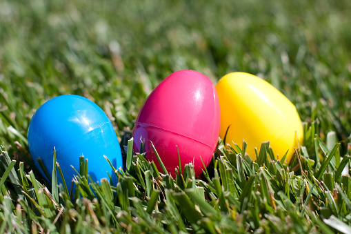 Three colorful Easter eggs sitting the the grass.