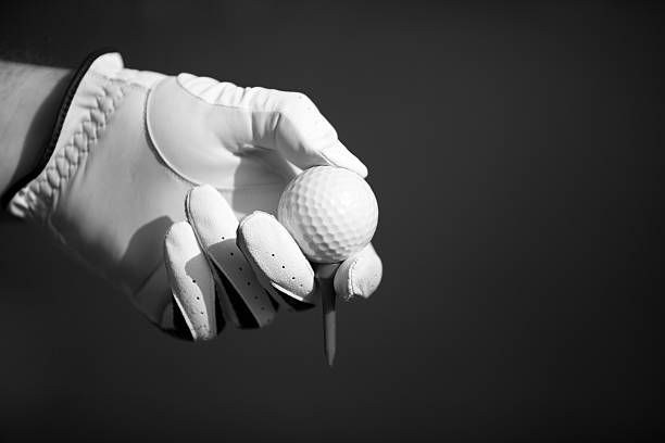 Human hand in golf glove holding ball
