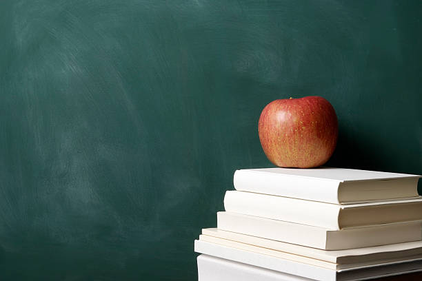 istock Red apple on stacked blank books in front of blackboard 471237689