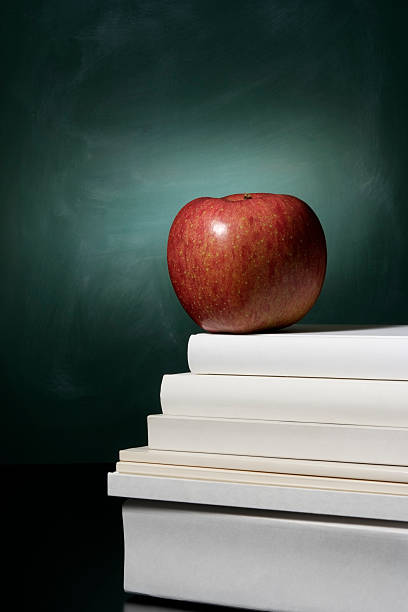 istock Red apple on stacked blank books in front of blackboard 471237709
