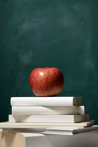 istock Red apple on stacked blank books in front of blackboard 471237717