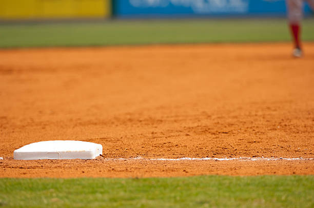 jugador de béisbol corriendo a terceros base en campo de béisbol durante partido de béisbol - baseball diamond baseball baseline grass fotografías e imágenes de stock