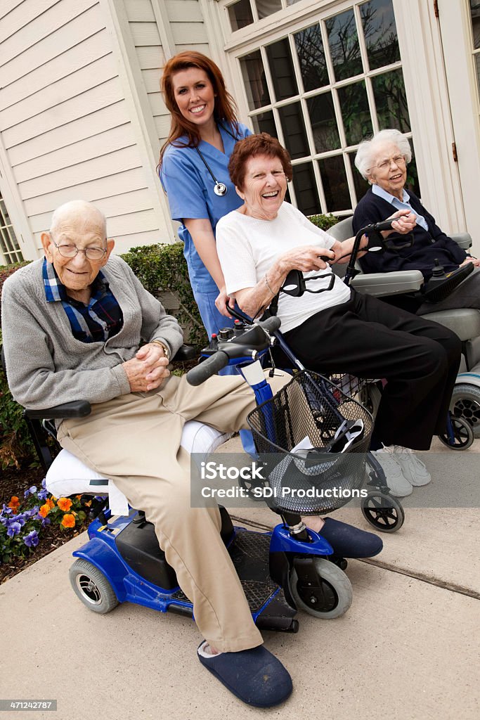 Cuidado enfermeira ajudando grupo de Senior adultos no carrinho motorizado - Foto de stock de 70 anos royalty-free