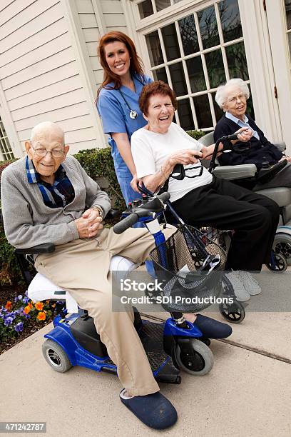 Foto de Cuidado Enfermeira Ajudando Grupo De Senior Adultos No Carrinho Motorizado e mais fotos de stock de 70 anos