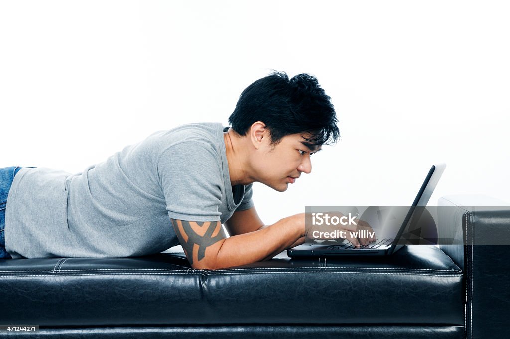 Jeune homme allongé sur un canapé et à l'aide d'un ordinateur portable - Photo de Adulte libre de droits