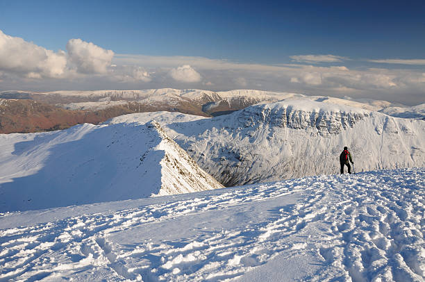 Walker on Helvellyn, English Lake District Walker admiring the view from Helvellyn over St Sunday Crag and Striding Edge in winter, English Lake District striding edge stock pictures, royalty-free photos & images