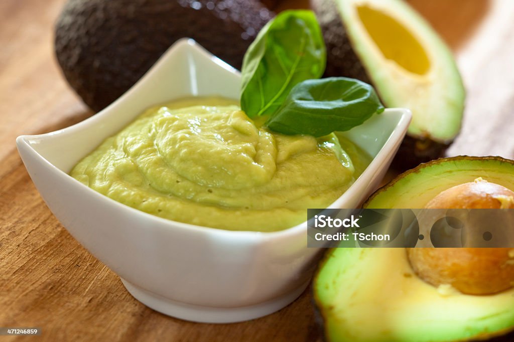 A bowl of green guacamole with leaves on side Avocado mousse with halved avocados Avocado Stock Photo