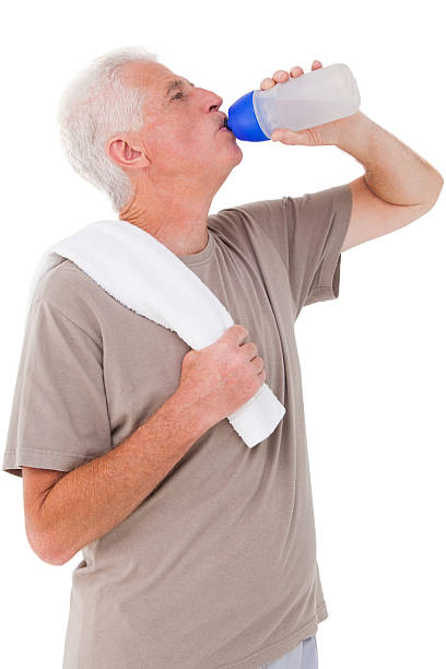 istock White haired man drinking from water bottle with towel 471247230
