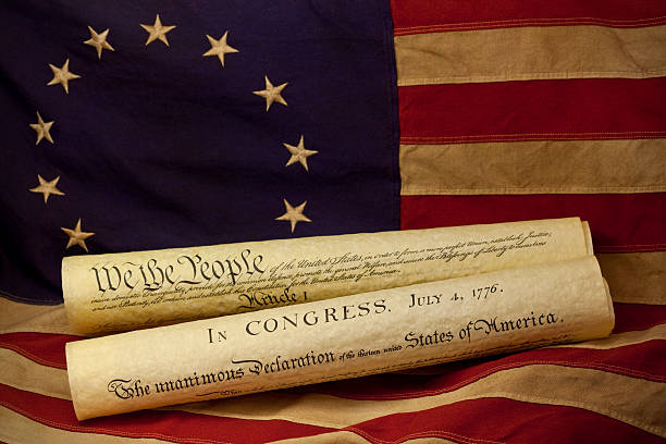We the People are the opening words of the preamble to the Constitution of the United States of America and the Declaration of Independence dated July 4, 1776. The documents are lying on an American flag, popularly attributed to Betsy Ross, that was designed during the American Revolutionary War and features 13 stars to represent the original 13 colonies.