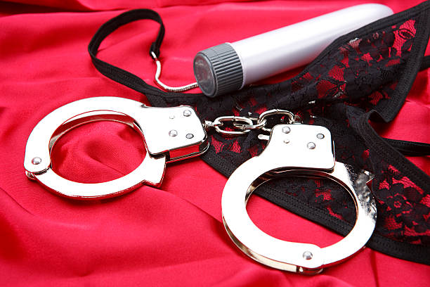 Fun in bed Handcuff, vibrator and thong on red satin Silk or Satin Panties stock pictures, royalty-free photos & images