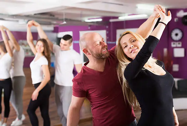 Smiling couples enjoying of partner dance indoor