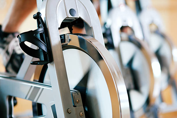 Bicycle exercising in gym Three people exercising in the gym, exercising for their legs and cardio training, only limbs and wheels to be seen spin bike stock pictures, royalty-free photos & images