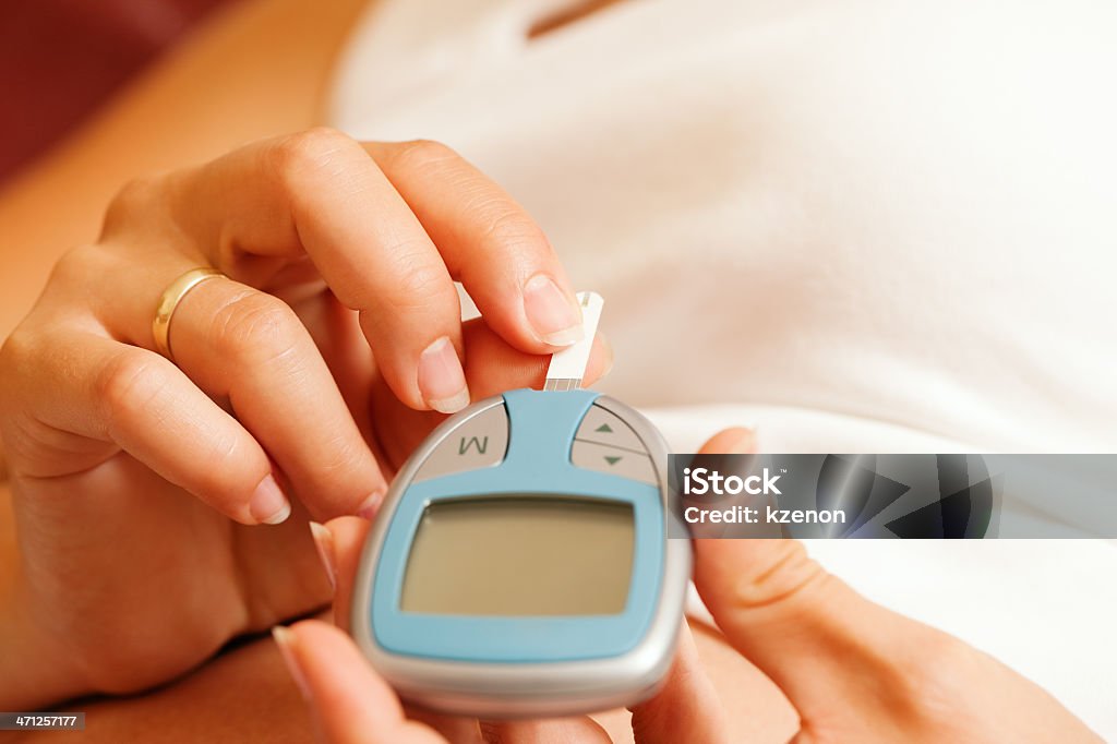 Woman holding glucose meter and testing blood for diabetes woman testing her blood glucose level to know whether or not she has diabetes Adult Stock Photo
