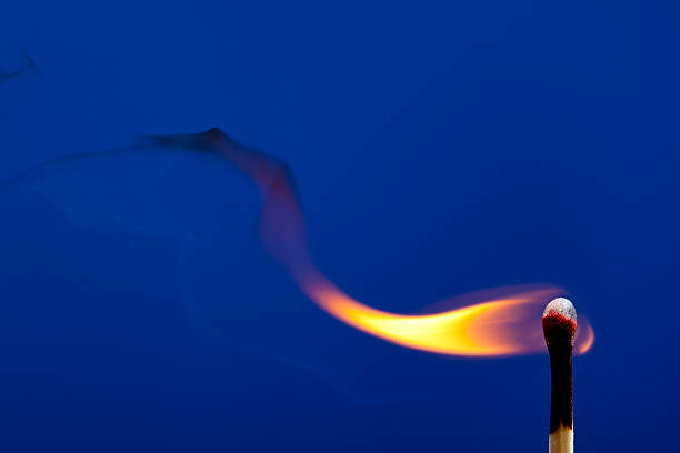 Burning match on a blue sky background