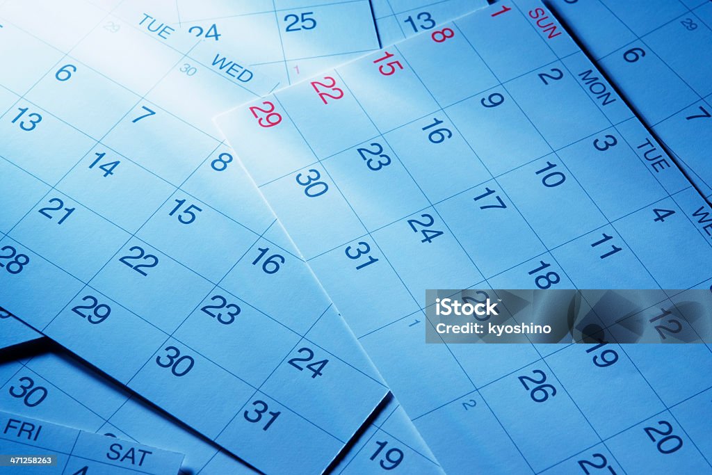 Blue tinted image of calendars with light rays Blue tinted image of stacked calendars with light rays. Calendar Stock Photo