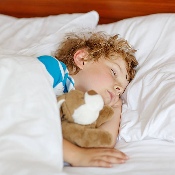 istock Little blond child sleeping in his bed with toy. 471258718
