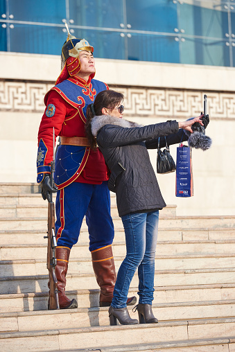 Ulan Bator, Mongolia - January 25, 2015: a wealthy mongolian woman take a selfie with a Mongolian Armed Forces Honorary Guard in Sukhbaatar Square.