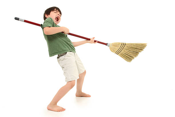 Air Guitar with Broom Stick Adorable seven year old boy playing air guitar with broom stick over white. air guitar stock pictures, royalty-free photos & images