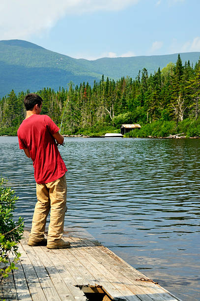 Young Man Working a Lure at Mountain Pond stock photo
