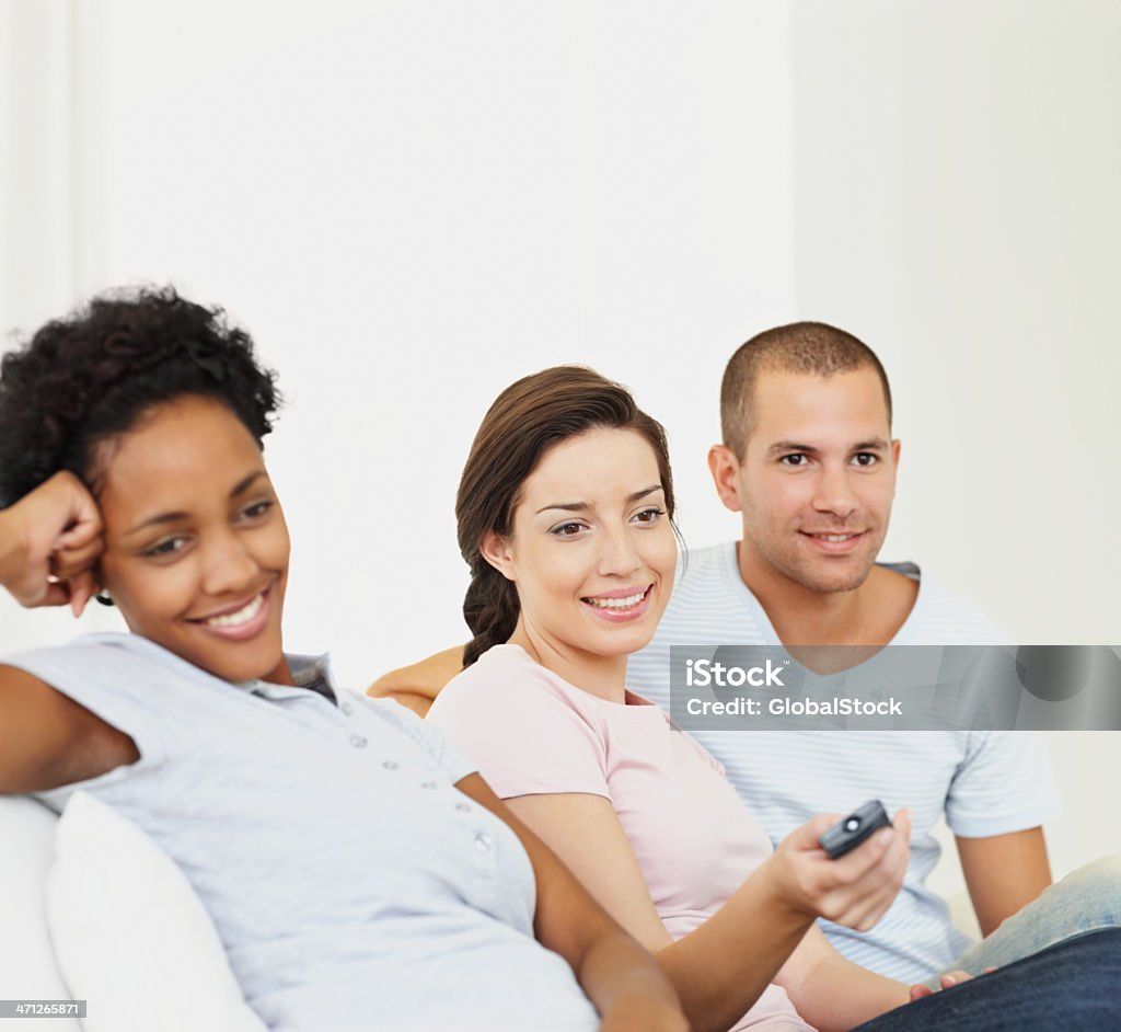Jovem e mulher sentada juntos enquanto assiste à televisão - Foto de stock de 20-24 Anos royalty-free