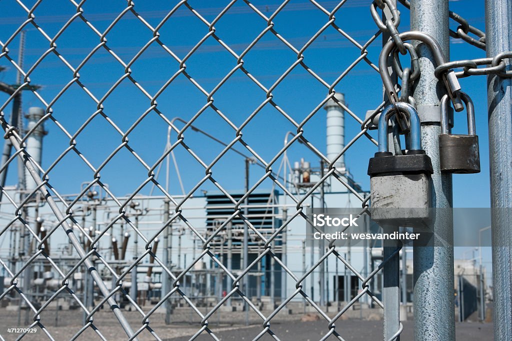 Gas Power Plant Behind Locked Gate A  padlocked gate on a chainlinked fence with a natural gas fired power plant in the the background. Chainlink Fence Stock Photo