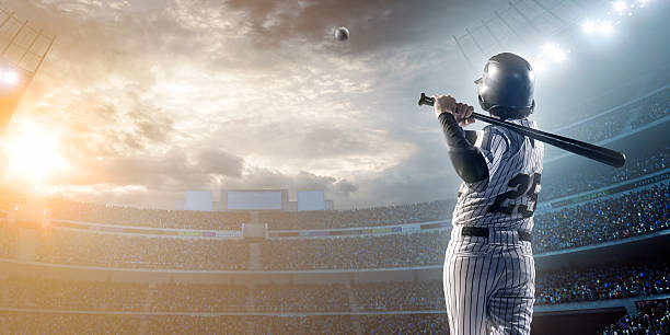 Baseball player hitting a ball in stadium A male baseballs batter makes a dramatic play by hitting a ball.  The stadium is blurred behind him. Only the lights of the stadium shine brightly, creating a halo effect around the bulbs. baseball sport photos stock pictures, royalty-free photos & images
