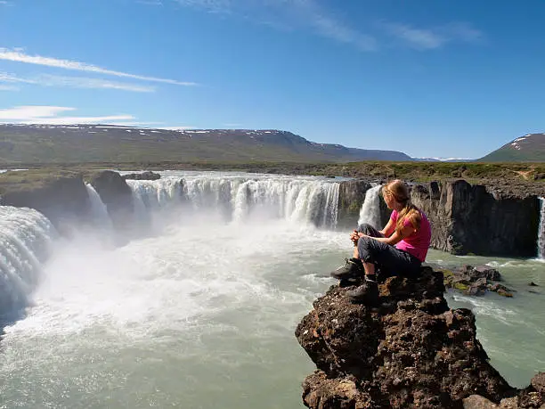 Woman Hiker resting At Godafoss Waterfall, Iceland.