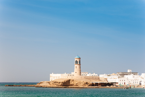 Lighthouse and old town at the coast of Sur, Ash Sharqiyah Region, North Eastern Oman. Coast of the Gulf of Oman. City of Sur, Oman