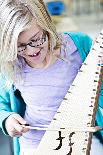 Girl Learning to Play a Bowed Psaltery Little girl in music class, learning to play an instrument called a Bowed Psaltery. psaltery stock pictures, royalty-free photos & images