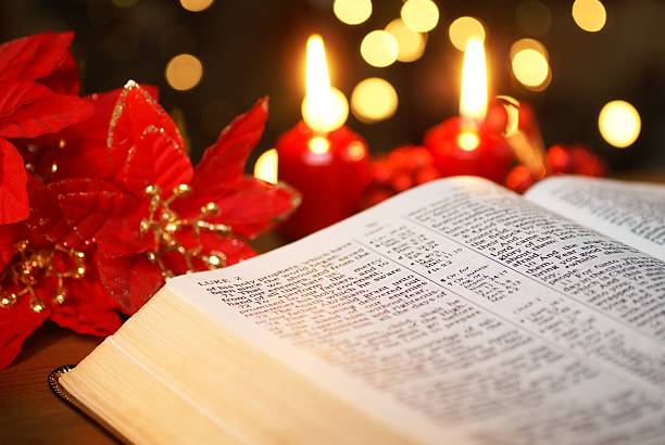 Close-up of bible open to Luke Christmas Story with candles Open Bible with Christmas story and Christmas decorations. Selective focus, shallow DOF. bible gospel stock pictures, royalty-free photos & images