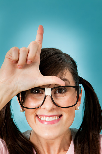 Shape Of An L On Her Forehead Happy Nerdy Young Woman Making An L On Her Forehead Stock Photo