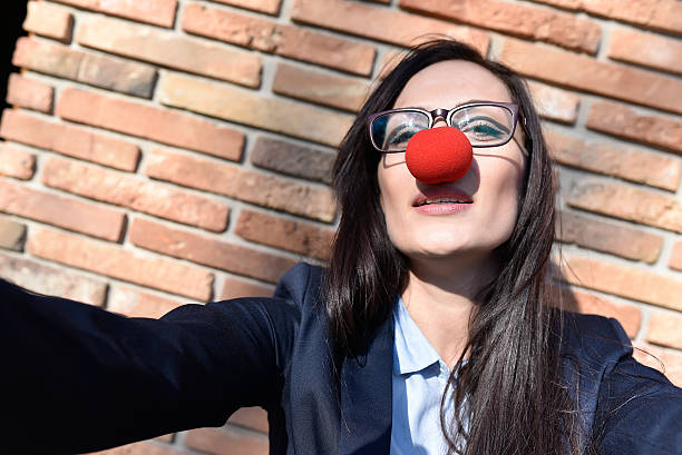 mujer de negocios con nariz de payaso tomando autofoto - curtain red color image clown fotografías e imágenes de stock