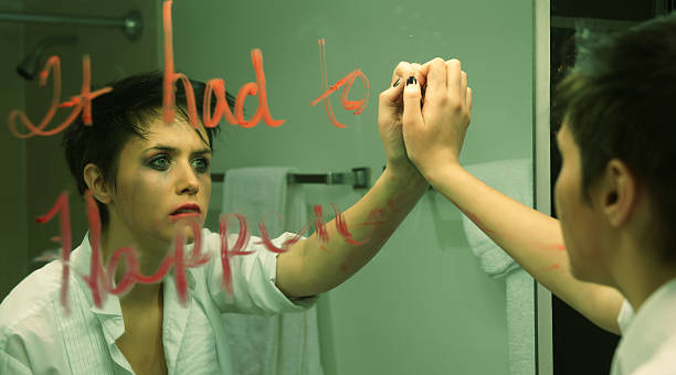 The Girl in Room Twelve The girl in room twelve staring at herself in motel bathroom mirror. "It had to happen" is scrawled on the mirror in lipstick. Cinematic aspect. mirror writing stock pictures, royalty-free photos & images
