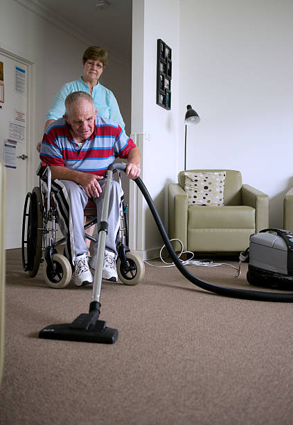 istock Senior man with a disability vacuuming floor 471292133