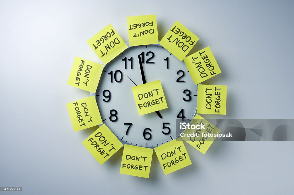 Wall clock with 'don't forget' notes all over "don't forget" adhesive note papers on the office clock Reminder Stock Photo