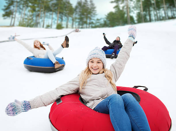 group of happy friends sliding down on snow tubes stock photo
