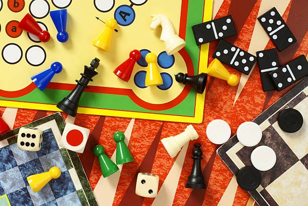 Multiple board games and pieces Top view of board games, pawns, chessmen, dominoes and dices. board game stock pictures, royalty-free photos & images