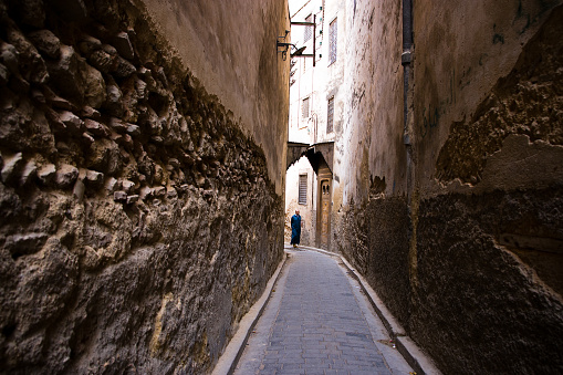 Fez, Morocco - September, 18 2008: Man walks in a narrow dark alley of the medieval medina of Fez el Bali.