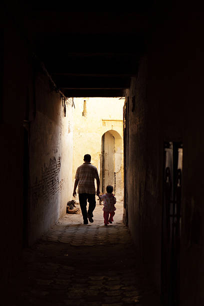 Fez, Morocco - October 16, 2009: Father and his little daughter are walking through the dark lanes of old city of Fez, Morocco.