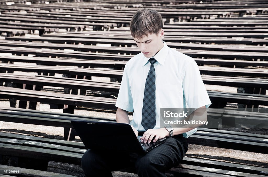 Chatting Young student working on laptop in the city park. Converted from Nikon RAW, Adobe RGB, desaturated colors.  18-19 Years Stock Photo